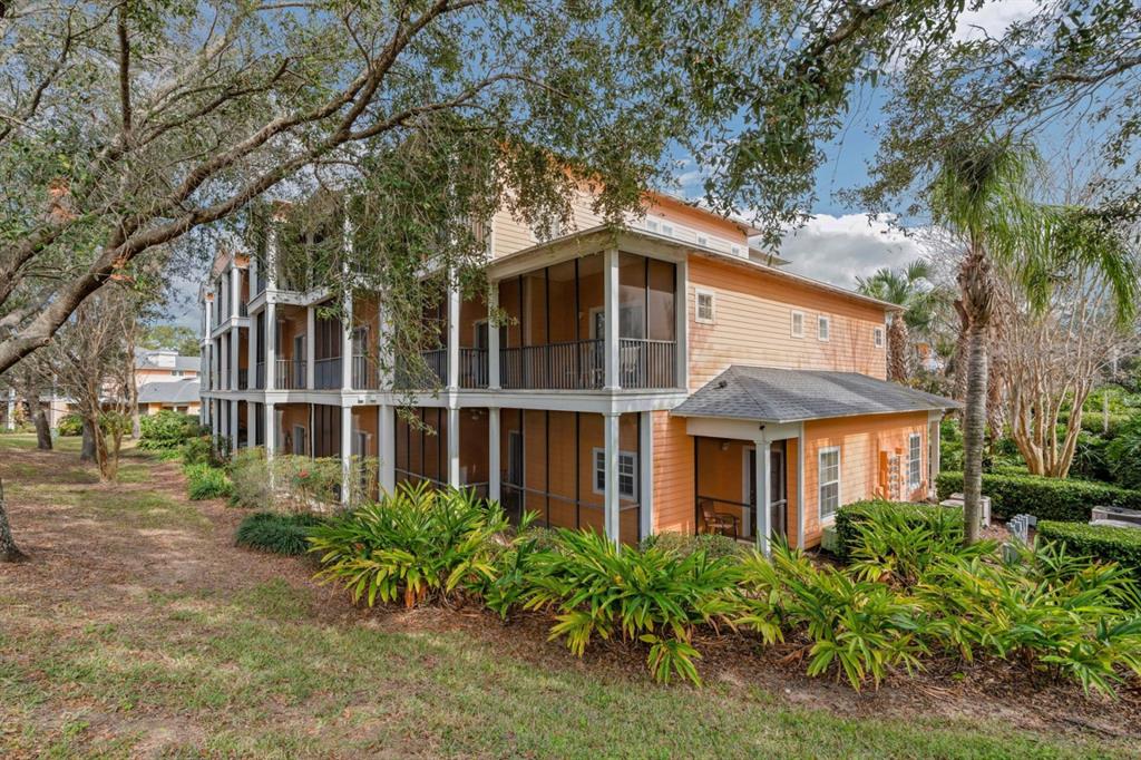 A three-story orange building features screened-in balconies and porches surrounded by trees and landscaping — 301 NEW PROVIDENCE PROMENADE UNIT 301, DAVENPORT, FL
