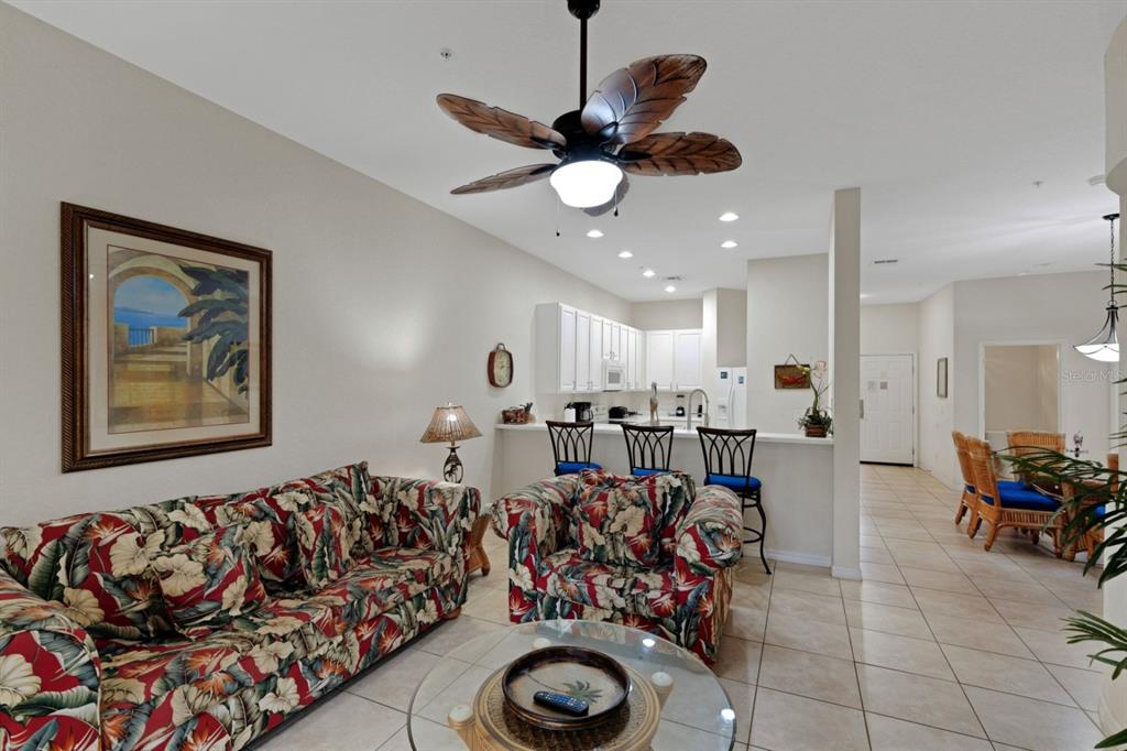 A living room with floral furniture, a ceiling fan, and an open kitchen with bar seating — 301 NEW PROVIDENCE PROMENADE UNIT 301, DAVENPORT, FL