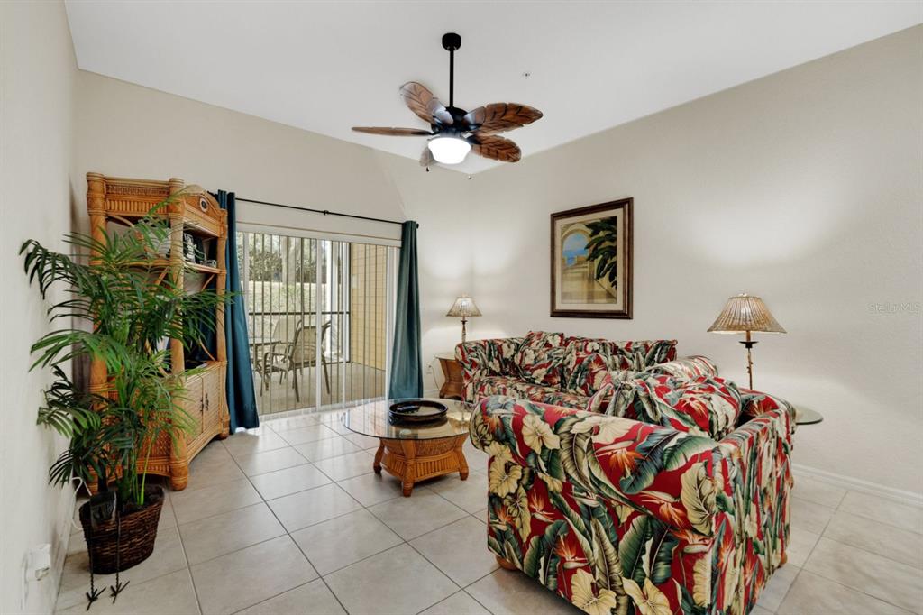 A living room features tile floors, a tropical-print sofa, and a sliding glass door — 301 NEW PROVIDENCE PROMENADE UNIT 301, DAVENPORT, FL