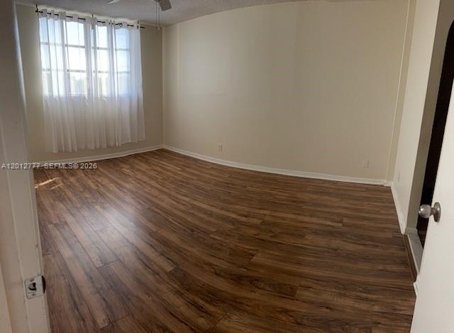 An empty bedroom features wood-look laminate flooring, beige walls, and white curtains over a window — 406 NW 68th Ave # 411, Plantation FL 33317, PLANTATION, FL