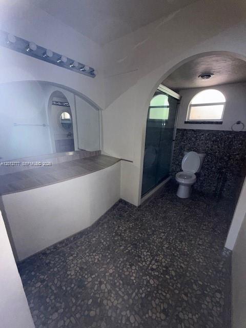 A bathroom features a vanity with a large mirror, a pebble-tiled floor, and a toilet — 406 NW 68th Ave # 411, Plantation FL 33317, PLANTATION, FL
