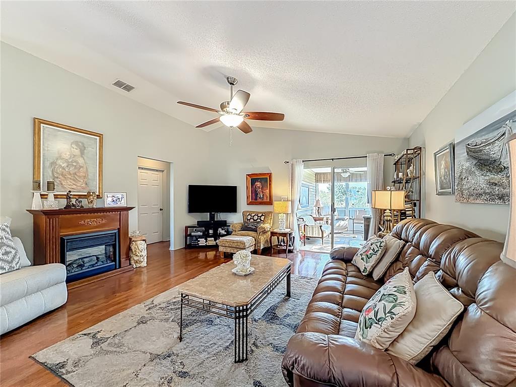 A living room features a fireplace, leather sofa, coffee table, and sliding glass doors — 4844 HERON RUN CIRCLE, LEESBURG, FL