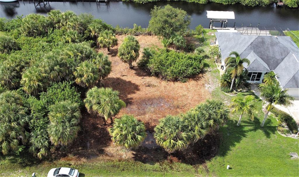 An aerial view shows a vacant, palm-filled lot next to a house and a canal — 18037 OHARA DRIVE, PORT CHARLOTTE, FL