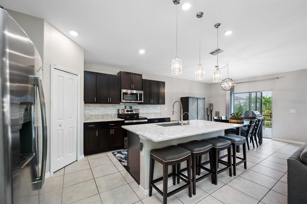 A screened-in patio features a dining set, outdoor seating, a grill, and a concrete floor — 6022 TREMEZA PLACE, PALMETTO, FL