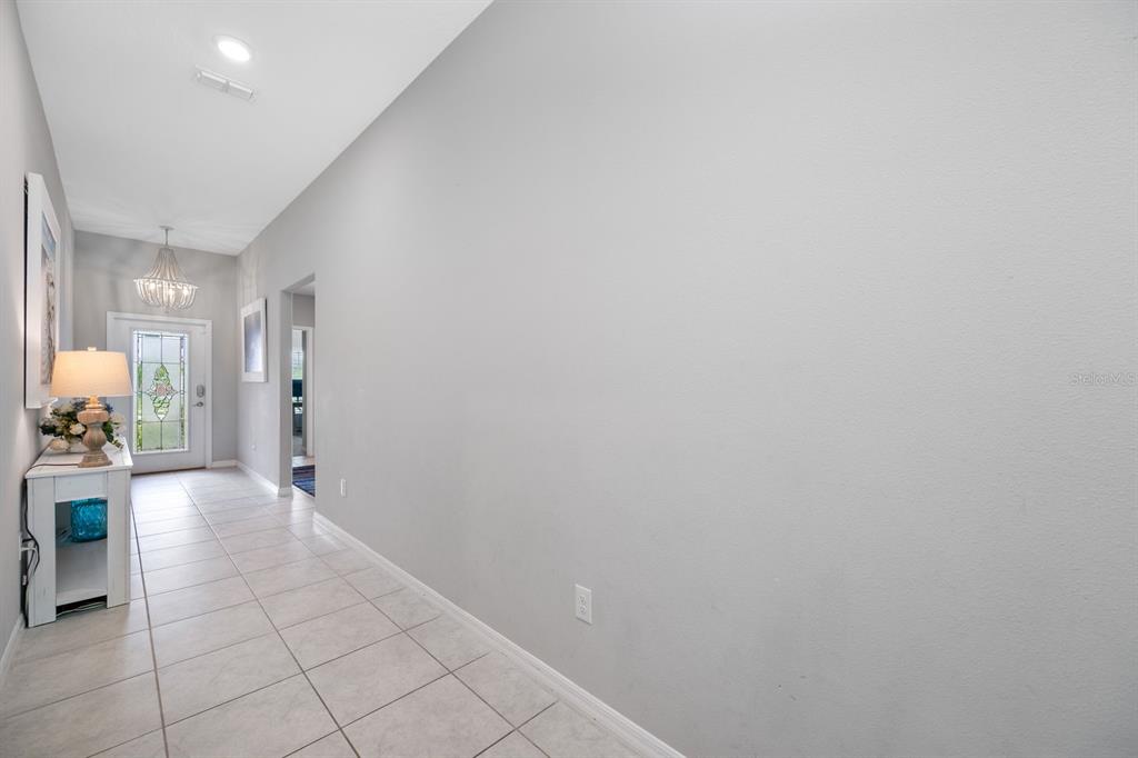 A long, light-gray hallway features white tile flooring, a console table, and a front door — 6022 TREMEZA PLACE, PALMETTO, FL