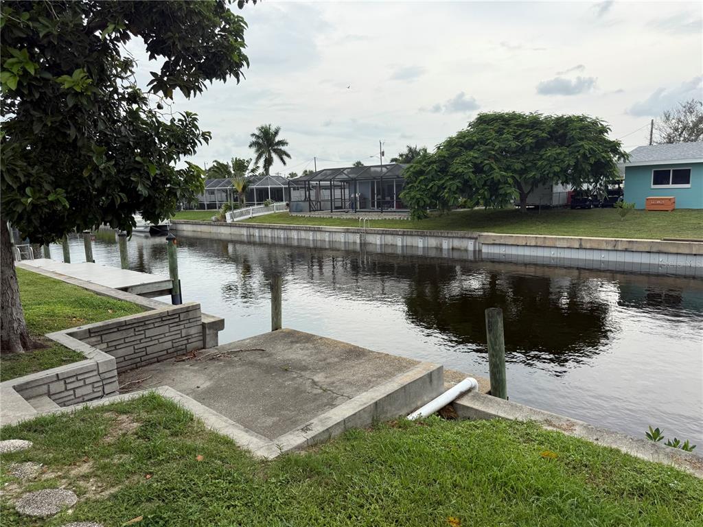 A concrete boat dock sits along a canal in front of several waterfront homes — 4339 S BAY CIRCLE, NORTH FORT MYERS, FL