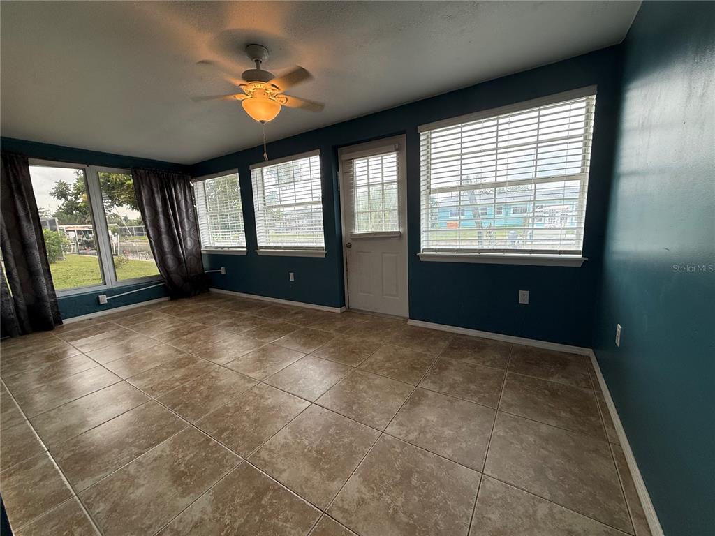 A sunroom features tile flooring, teal walls, a ceiling fan, and multiple windows with blinds — 4339 S BAY CIRCLE, NORTH FORT MYERS, FL