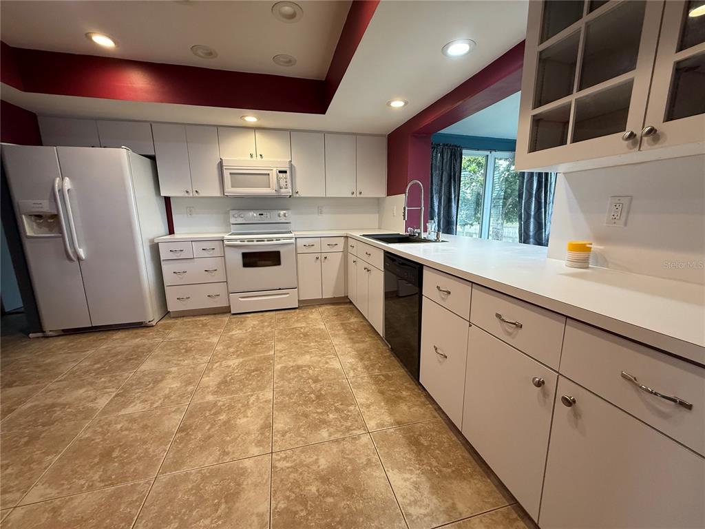 A kitchen features white cabinets, white appliances, tiled flooring, and a dark sink faucet — 4339 S BAY CIRCLE, NORTH FORT MYERS, FL