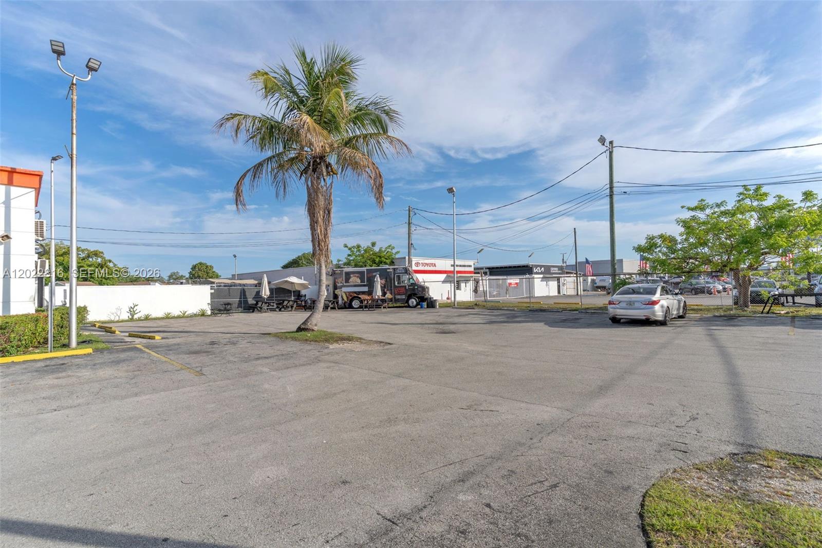 An asphalt parking lot features a single palm tree, a food truck, and parked cars — 30005 S Dixie Highway, Homestead FL 33033, HOMESTEAD, FL