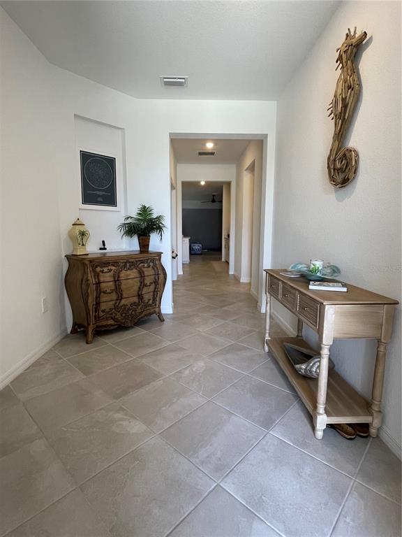 A tiled hallway features a wooden chest, a console table, and a seahorse wall decoration — 11321 PINOT DRIVE, VENICE, FL
