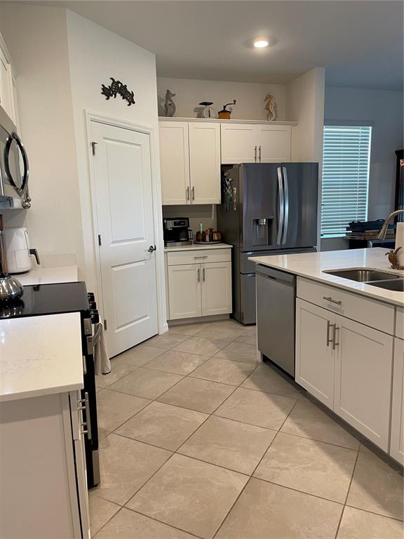 A kitchen features white cabinets, stainless steel appliances, a center island, and tiled flooring — 11321 PINOT DRIVE, VENICE, FL