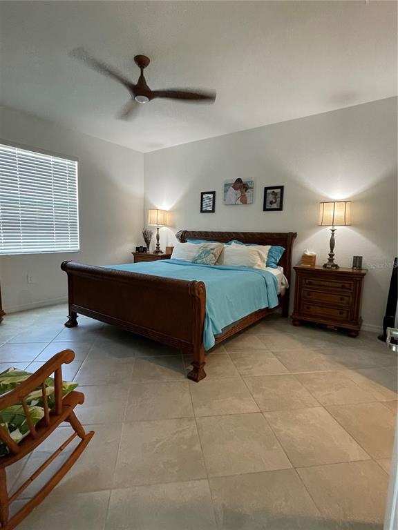 A bedroom features a wooden sleigh bed, two nightstands with lamps, and tile flooring — 11321 PINOT DRIVE, VENICE, FL