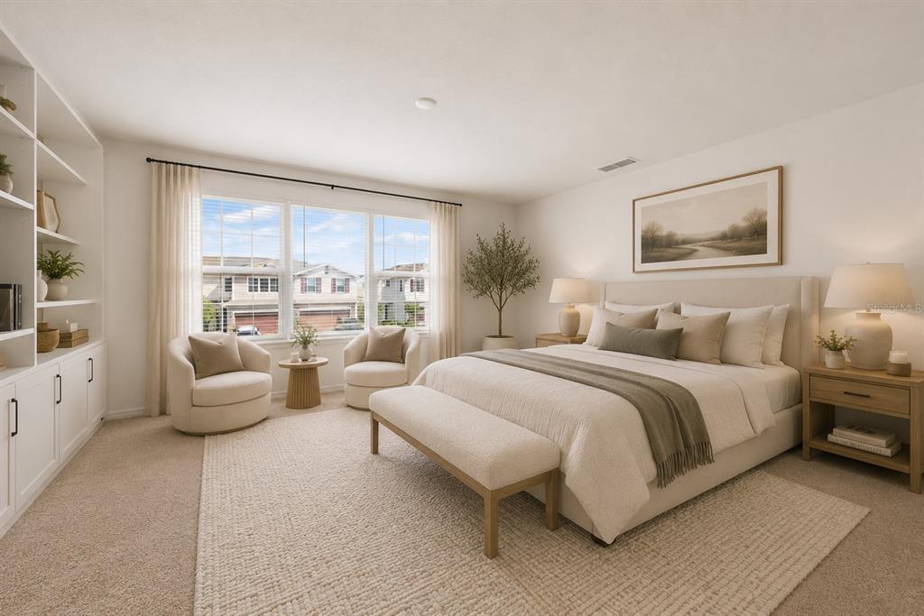 A bright bedroom features a queen bed, two armchairs, built-in shelving, and large windows — 1259 WISPY CYPRESS DRIVE, KISSIMMEE, FL