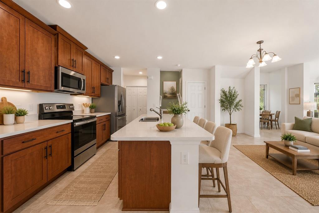 A kitchen with wood cabinets, stainless steel appliances, and a large island with bar seating — 1259 WISPY CYPRESS DRIVE, KISSIMMEE, FL