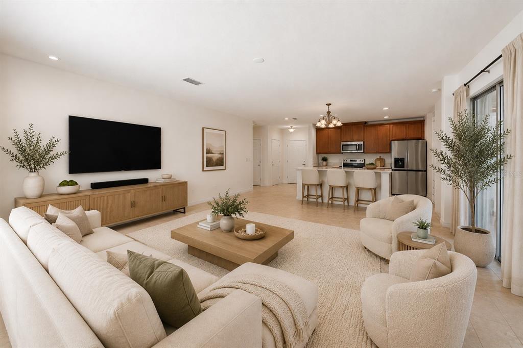 An open-concept living room and kitchen featuring neutral furniture, a large television, and tile flooring — 1259 WISPY CYPRESS DRIVE, KISSIMMEE, FL