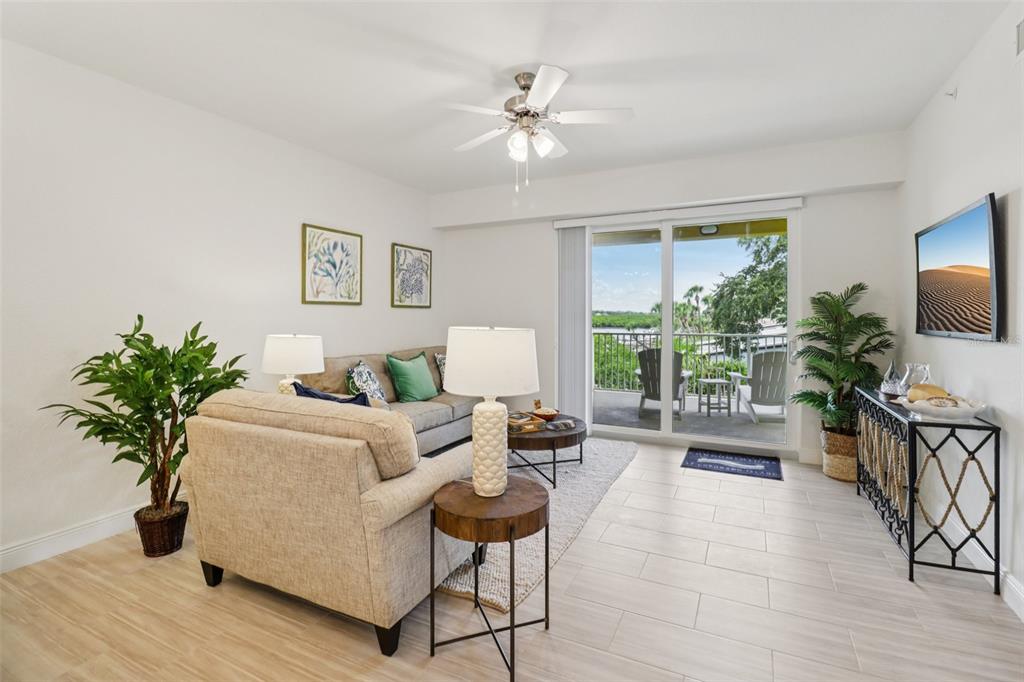 A living room features a sofa, a ceiling fan, and a sliding door to a balcony — 7 RIVERWALK DRIVE UNIT 406, NEW SMYRNA BEACH, FL