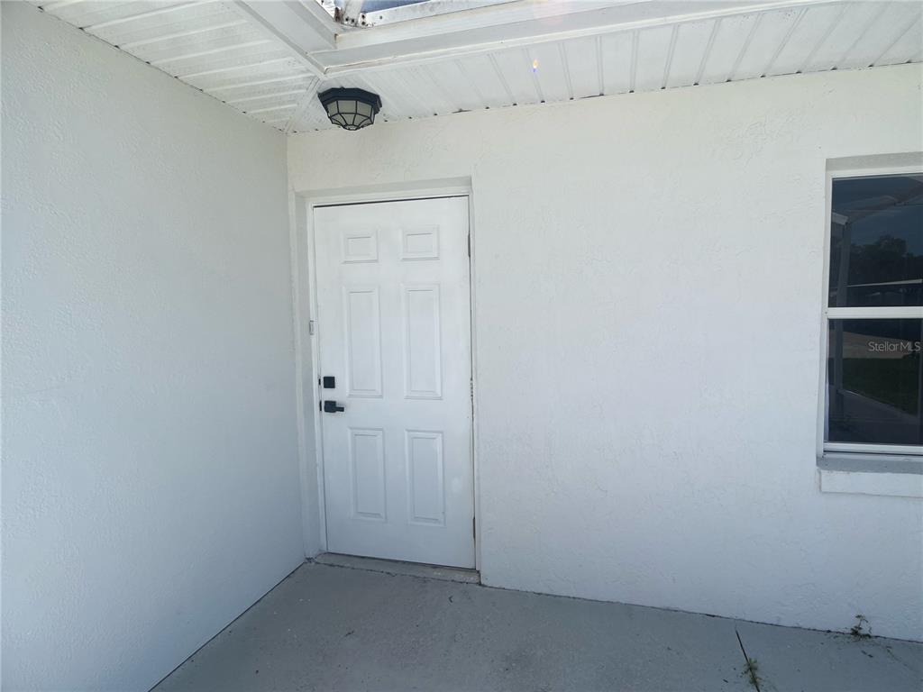 A white exterior door and a window are located on a covered concrete patio — 2954 PEACH STREET, LEESBURG, FL