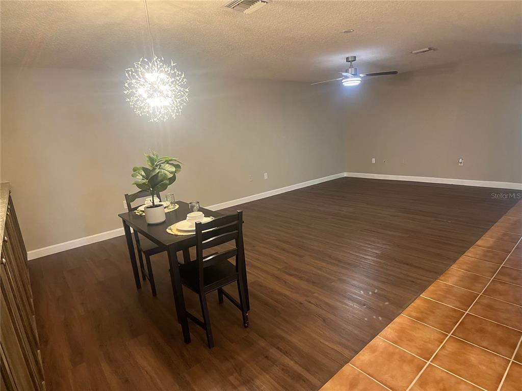 A dining area with wood-look flooring features a small table and a modern pendant light — 2954 PEACH STREET, LEESBURG, FL