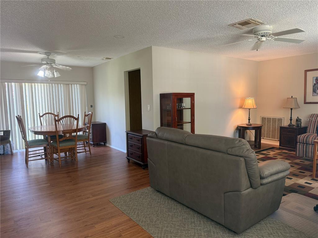 A living room with wood-look flooring and a dining area with a sliding glass door — 4238 PINEFIELD AVENUE, HOLIDAY, FL