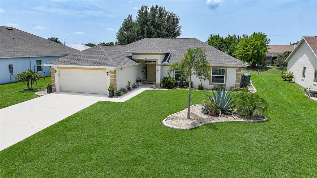 A single-story house with a two-car garage, light-colored stucco walls, and a landscaped front yard — 26403 RAMPART BOULEVARD, PUNTA GORDA, FL