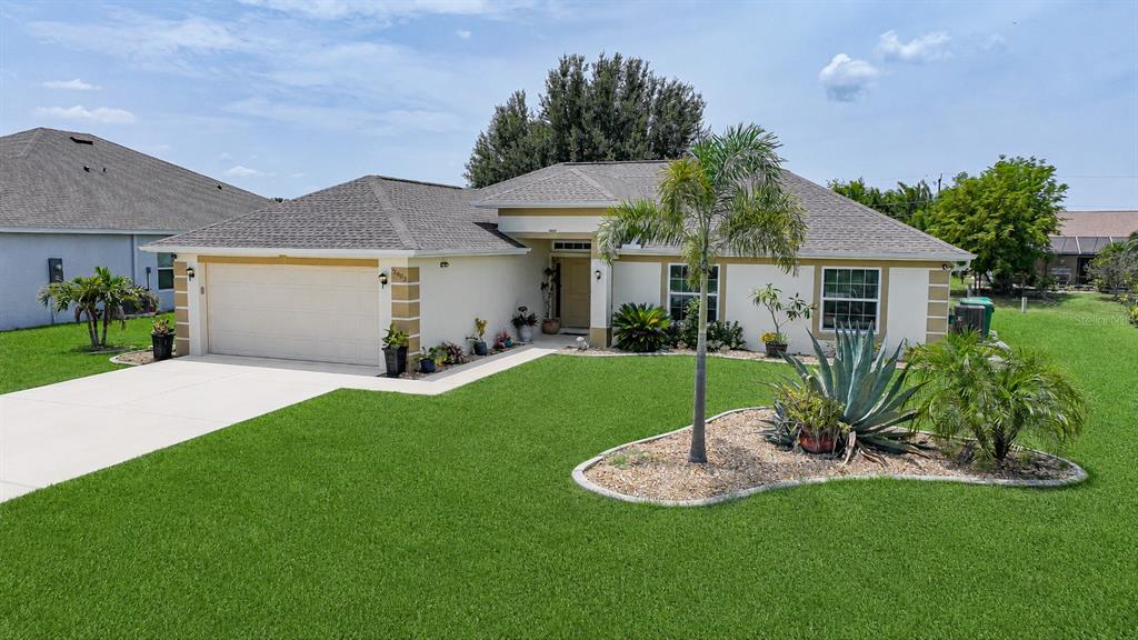 A single-story house with a two-car garage, a palm tree, and a landscaped front yard — 26403 RAMPART BOULEVARD, PUNTA GORDA, FL