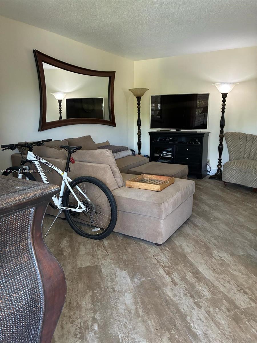 A living room features a beige sectional sofa, a bicycle, and a television on a stand — 2050 NE 39th St # 311, Lighthouse Point FL 33064, LIGHTHOUSE POINT, FL