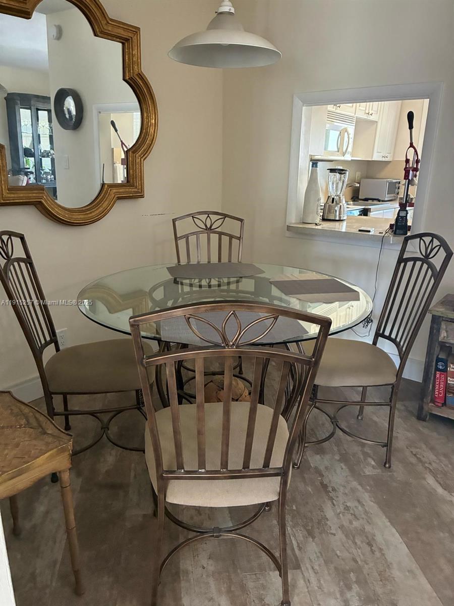 A dining area features a glass-topped table with four metal chairs and a wall mirror — 2050 NE 39th St # 311, Lighthouse Point FL 33064, LIGHTHOUSE POINT, FL