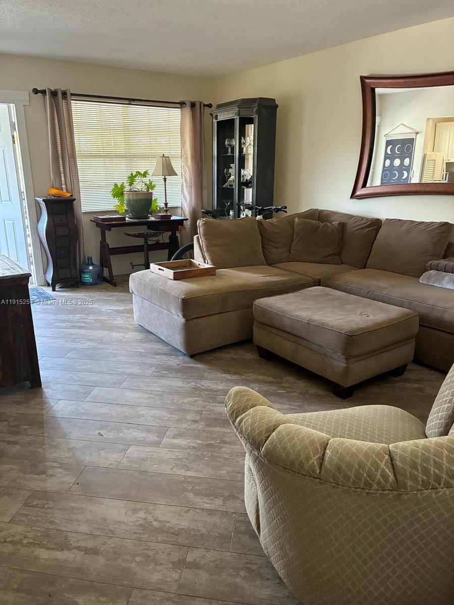 A living room features a brown sectional sofa, an ottoman, and light wood-look tile flooring — 2050 NE 39th St # 311, Lighthouse Point FL 33064, LIGHTHOUSE POINT, FL
