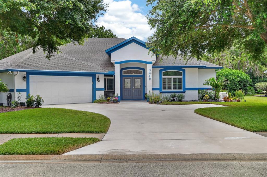 A single-story house with white stucco walls, blue trim, and a concrete driveway — 3645 CHRISTA COURT, ORMOND BEACH, FL