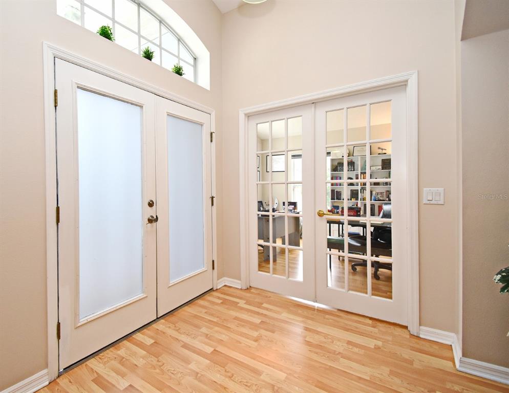 An entryway features light wood flooring, double frosted glass front doors, and French doors leading inside — 2634 GOLD DUST CIRCLE, KISSIMMEE, FL