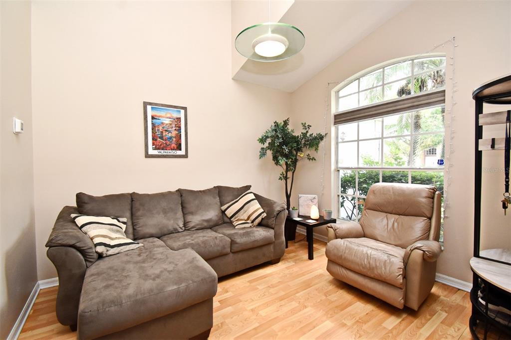 A living room features a brown sectional sofa, a recliner, and a large arched window — 2634 GOLD DUST CIRCLE, KISSIMMEE, FL