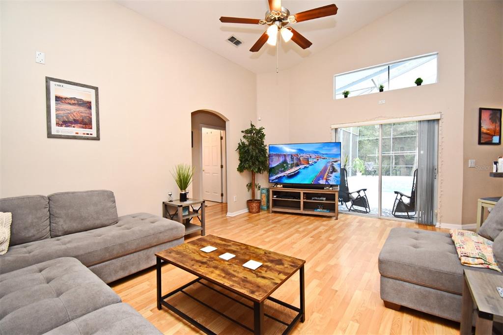 A living room with gray sectionals, a wood coffee table, and a sliding glass door — 2634 GOLD DUST CIRCLE, KISSIMMEE, FL