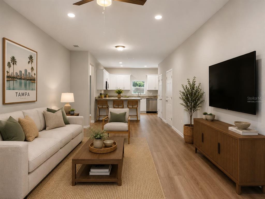 This living room features a sofa, coffee table, television, and an open kitchen in back — 5020 FINDERS COURT, TAMPA, FL