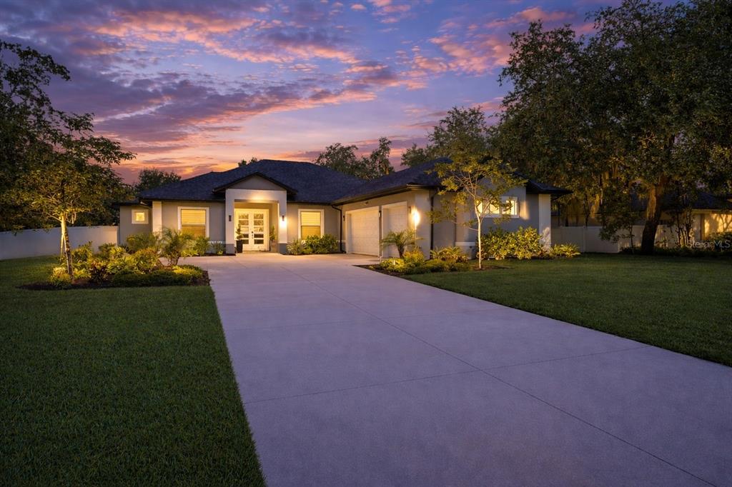 A single-story house with a concrete driveway and a sunset sky in the background — 2766 SHANNIN DRIVE, ST CLOUD, FL