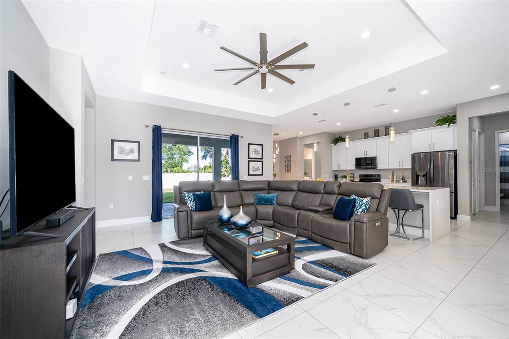 A living room features a grey sectional sofa, a television, and a tray ceiling — 2766 SHANNIN DRIVE, ST CLOUD, FL