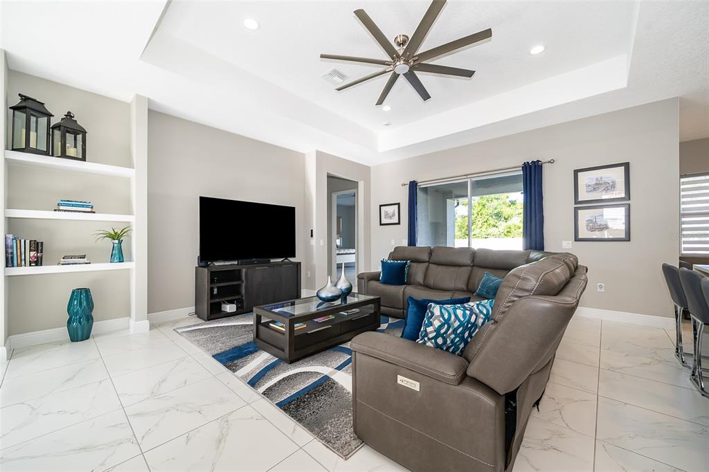 A modern kitchen features white cabinetry, quartz countertops, stainless steel appliances, and light tile flooring — 2766 SHANNIN DRIVE, ST CLOUD, FL