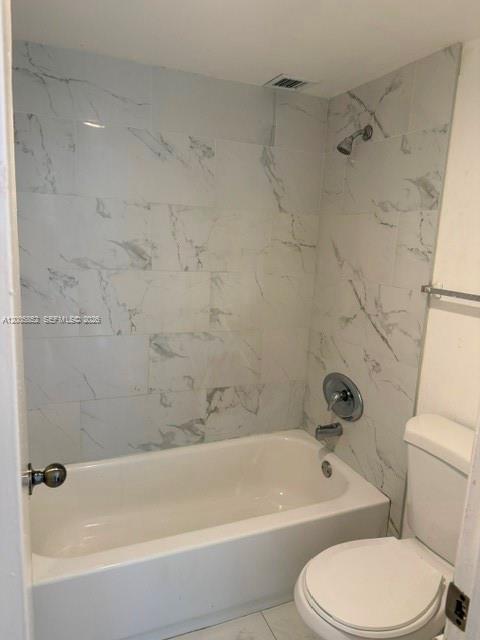 A bathroom features a white bathtub with a marble-tiled shower surround and a white toilet — 7031 Environ Blvd # 221, Lauderhill FL 33319, LAUDERHILL, FL