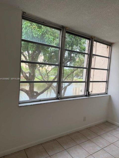 A room with tiled floors and a large window overlooking a tree and water — 7031 Environ Blvd # 221, Lauderhill FL 33319, LAUDERHILL, FL