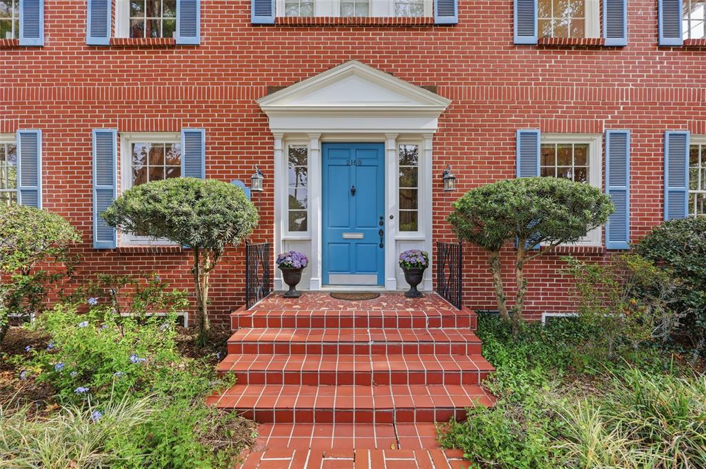 A red brick house features a blue front door, matching shutters, and tiled front steps — 2150 NW 7TH LANE, GAINESVILLE, FL