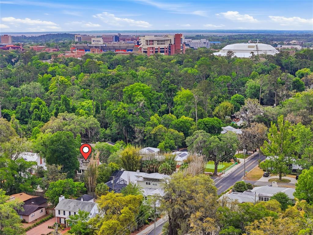 An aerial view shows a residential neighborhood with a red location pin and distant stadium — 2150 NW 7TH LANE, GAINESVILLE, FL