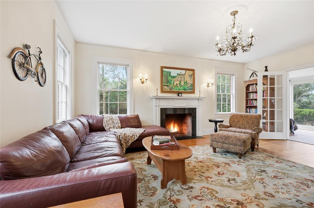 A living room features a leather sectional, fireplace, patterned rug, and a crystal chandelier — 2150 NW 7TH LANE, GAINESVILLE, FL