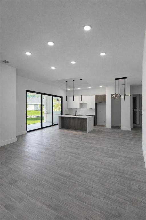 A modern open-concept kitchen features a dark wood island, white cabinetry, and gray tile flooring — 1089 CORNELIUS BOULEVARD, PORT CHARLOTTE, FL