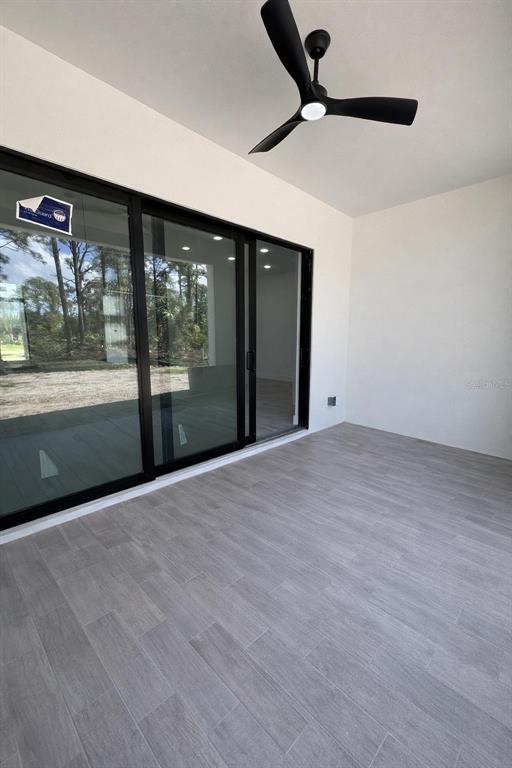 A covered patio features gray tile flooring, a black ceiling fan, and large sliding glass doors — 1089 CORNELIUS BOULEVARD, PORT CHARLOTTE, FL