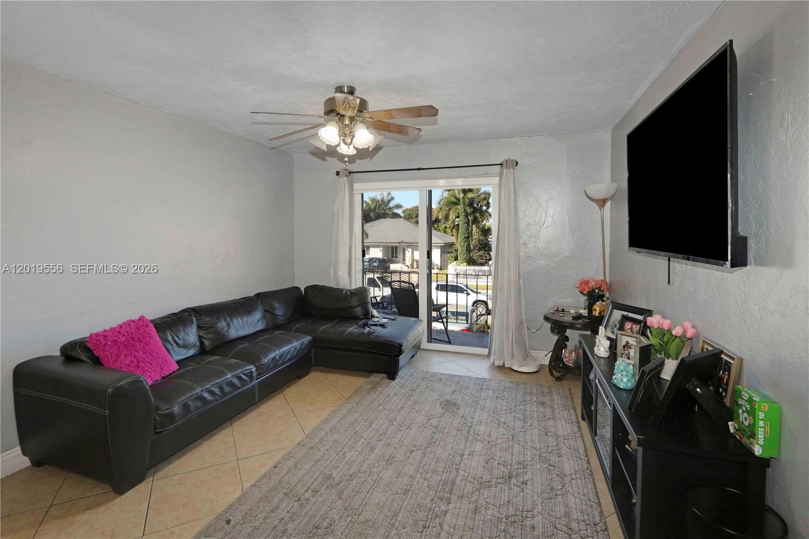 A living room features a black sectional sofa, a television, and a sliding glass door — 1275 W 35th St # 45B, Hialeah FL 33012, HIALEAH, FL