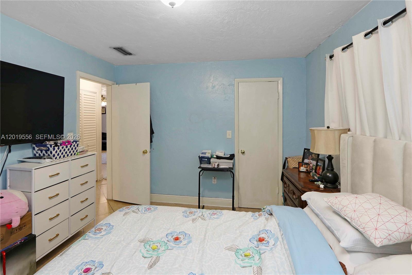 A bedroom features light blue walls, a white dresser, a bed, and two closed doors — 1275 W 35th St # 45B, Hialeah FL 33012, HIALEAH, FL