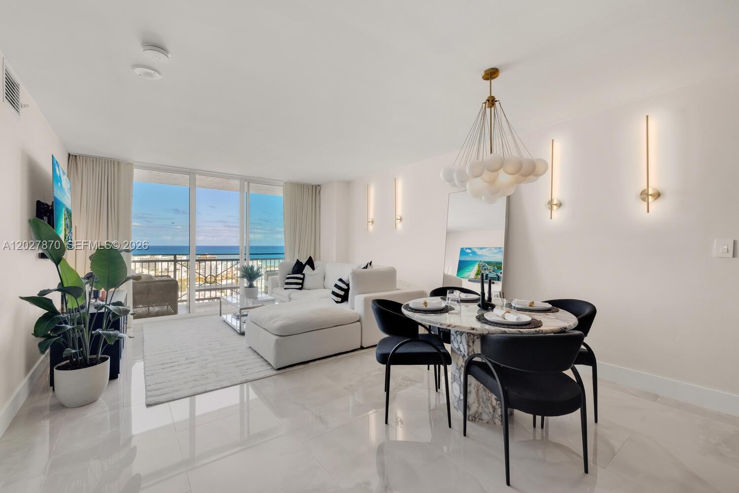 A modern living and dining room features white tile floors, a marble table, and ocean views — 90 Alton Rd # 2207, Miami Beach FL 33139, MIAMI BEACH, FL