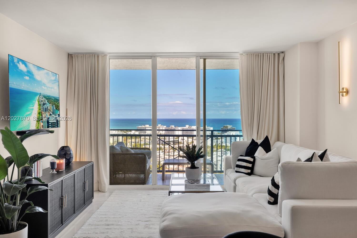 A bright living room features a white sectional sofa, a black media console, and balcony views — 90 Alton Rd # 2207, Miami Beach FL 33139, MIAMI BEACH, FL