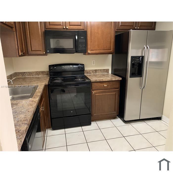 A kitchen features wood cabinets, a black stove, a microwave, and a stainless steel refrigerator — 19791 SW 114th Ave # 331, Miami FL 33157, MIAMI, FL