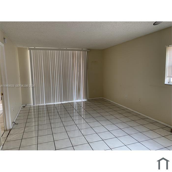 An empty room features white tiled floors, beige walls, and a large sliding glass door — 19791 SW 114th Ave # 331, Miami FL 33157, MIAMI, FL