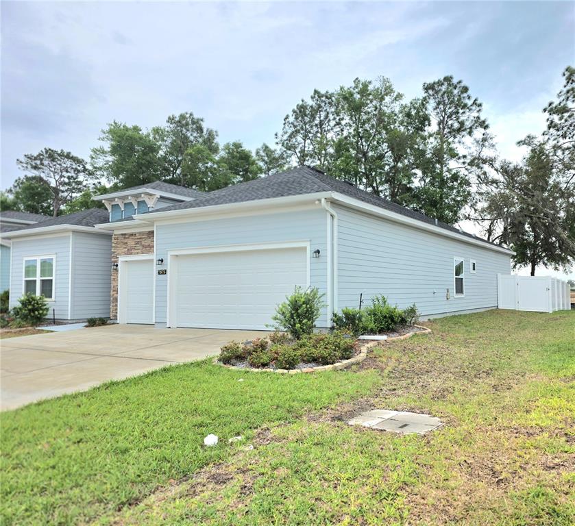 A light blue single-story house features a two-car garage, stone accents, and a grassy yard — 7875 SW 74TH LOOP, OCALA, FL